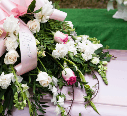 En kista dekorerad med vita och rosa blommor och ett rosa band.