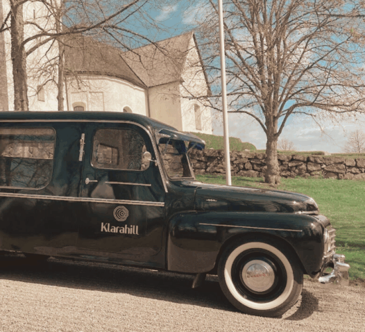 En svart bil med texten "Kundbil" står parkerad framför en kyrka.
